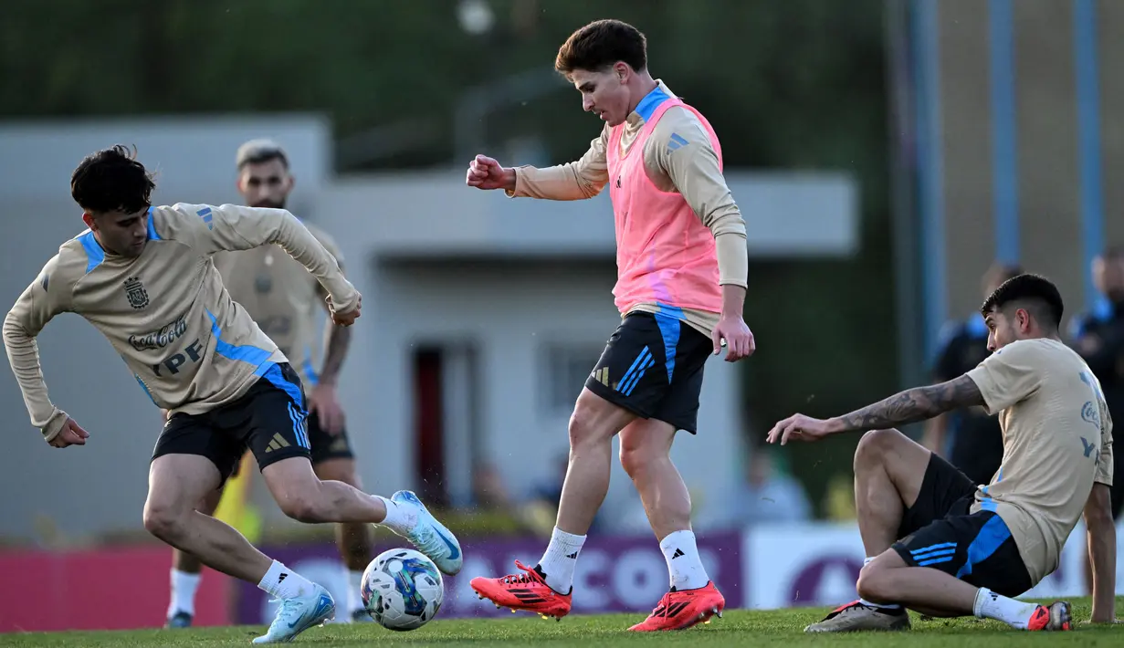 Pemain tengah tim nasional Argentina, Facundo Buonanotte (kanan) berebut bola dengan Julian Alvarez (tengah) saat sesi latihan di Ezeiza, provinsi Buenos Aires, pada 12 November 2024. (LUIS ROBAYO/AFP)