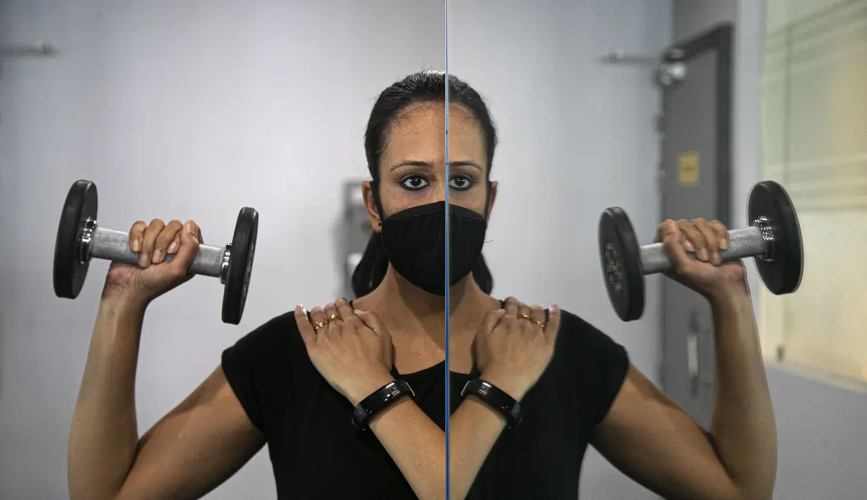 Seorang wanita India terlihat di cermin saat berolahraga di tempat gym yang dibuka kembali setelah lockdown di Gauhati, India, Rabu, (5/8/2020). India memiliki jumlah virus coronavirus tertinggi ketiga di dunia setelah Amerika Serikat dan Brasil. (AP Photo/Anupam Nath)