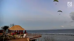 Wisatawan melakukan tandem paralayang di Bukit Riug, Nusa Dua, Bali (30/6). Kegiatan paralayang tandem dengan mengandalkan angin pantai sudah lebih dari satu tahun digemari para wisatawan mancanegara dan lokal. (Merdeka.com/Arie Basuki)