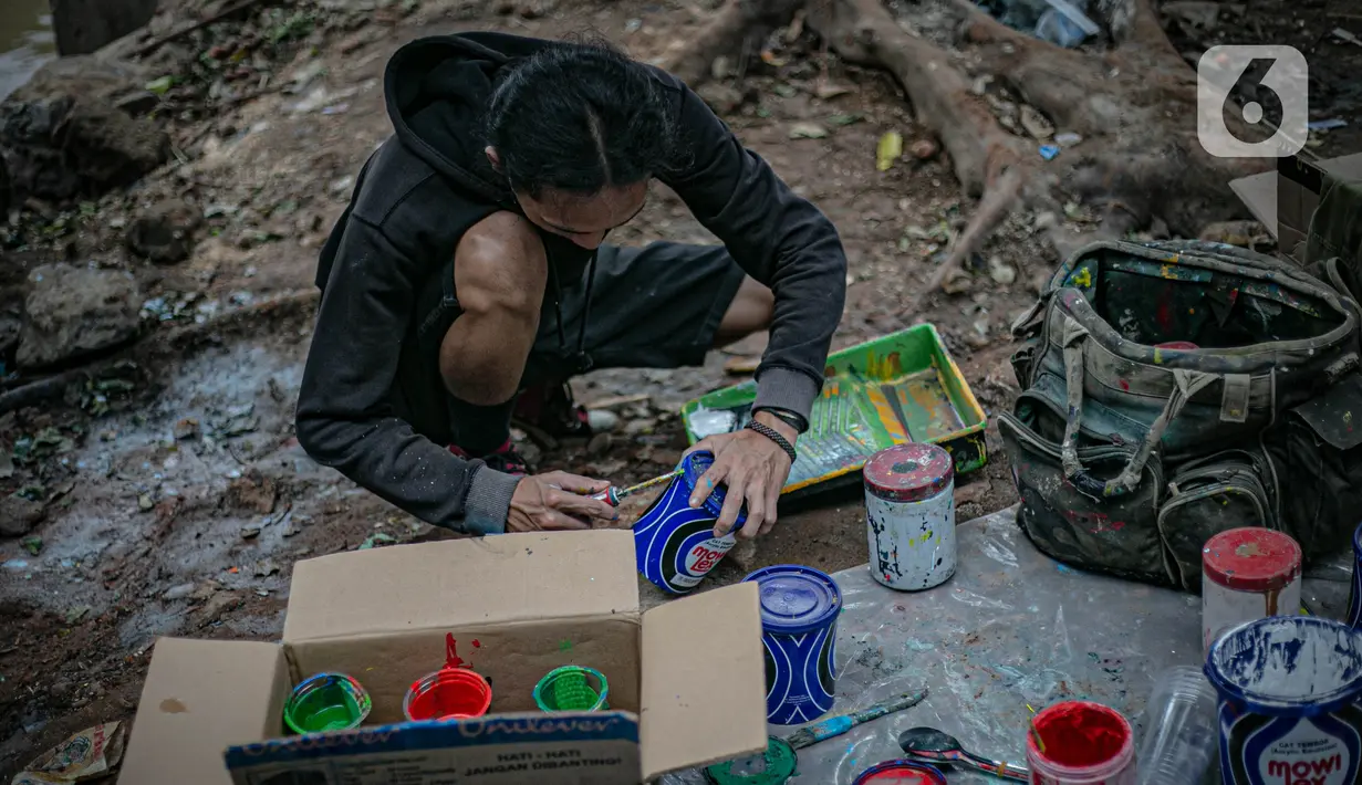 Mahasiswa Institut Kesenian Jakarta (IKJ) menyiapkan cat untuk membuat mural di kolong Jembatan Pegangsaan, Menteng, Jakarta, Selasa (26/1/2021). Pembuatan mural tersebut merupakan bagian dari pembangunan taman kolong jembatan oleh Pemprov DKI Jakarta. (Liputan6.com/Faizal Fanani)