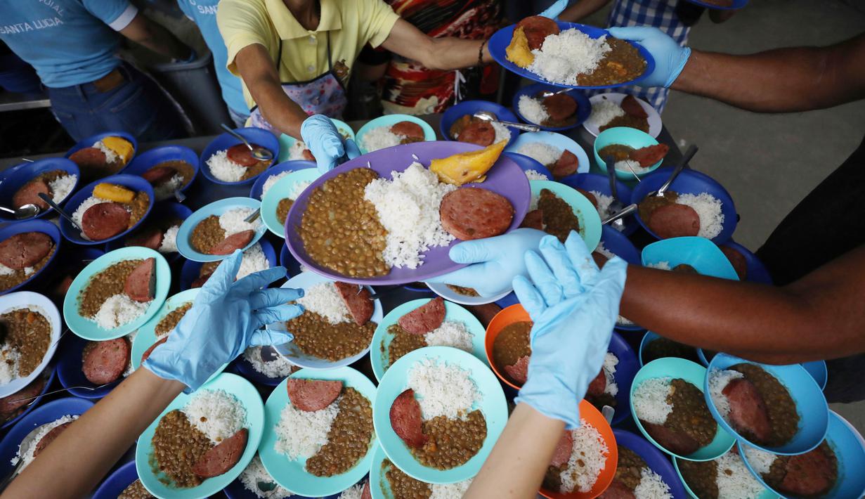 Relawan menyiapkan makanan untuk pengungsi Venezuela di tempat penampungan Divina Providencia, La Parada, Cucuta, Kolombia, Senin (18/2). Makanan terdiri dari kacang-kacangan, daging bologna, nasi, dan sepotong pisang. (AP Photo/Fernando Vergara)