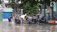 Warga mencuci motor saat banjir yang merendam kawasan Benhil, Jakarta, Selasa (25/2/2020). Hujan yang mengguyur wilayah tersebut membuat air sungai meluap sehingga menyebabkan Banjir setinggi pinggang orang dewasa. (Liputan6.com/Angga Yuniar)