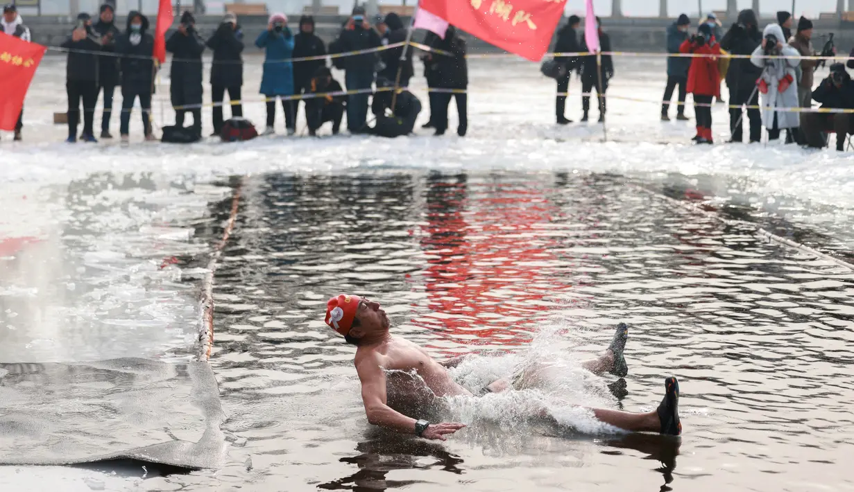Seorang penggemar renang musim dingin melompat ke danau yang sebagian beku di Shenyang, di provinsi Liaoning, China pada 25 Januari 2022. Berenang di musim dingin adalah kegiatan olahraga yang jarang dijumpai kecuali di beberapa negara dengan musim dingin yang cukup panjang. (STR/AFP)