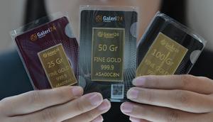 Seorang karyawan menunjukkan emas batangan 25, 50, dan 100 gram produksi Galeri 24, anak perusahaan dari PT Pegadaian (Persero), di Jakarta pada 14 April 2025. (BAY ISMOYO/AFP)