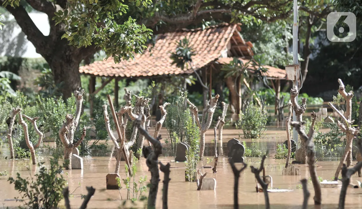 Kondisi makam saat terendam banjir di Pulo Nangka, Jakarta, Minggu (23/2/2020). Ismail mengaku banjir tersebut merupakan yang ketiga kalinya terjadi sejak awal tahun 2020 yang diperparah setelah adanya apartemen karena saluran air tertutup beton pembangunan. (merdeka.com/Iqbal S. Nugroho)
