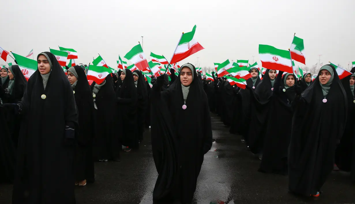 Para siswi mengibarkan bendera Iran dalam upacara peringatan 40 tahun Revolusi Islam Iran di Menara Kebebasan, Teheran, Senin (11/2). Revolusi Islam Iran dianggap sebagai hari kemenangan bagi negeri tersebut. (AP Photo/Vahid Salemi)
