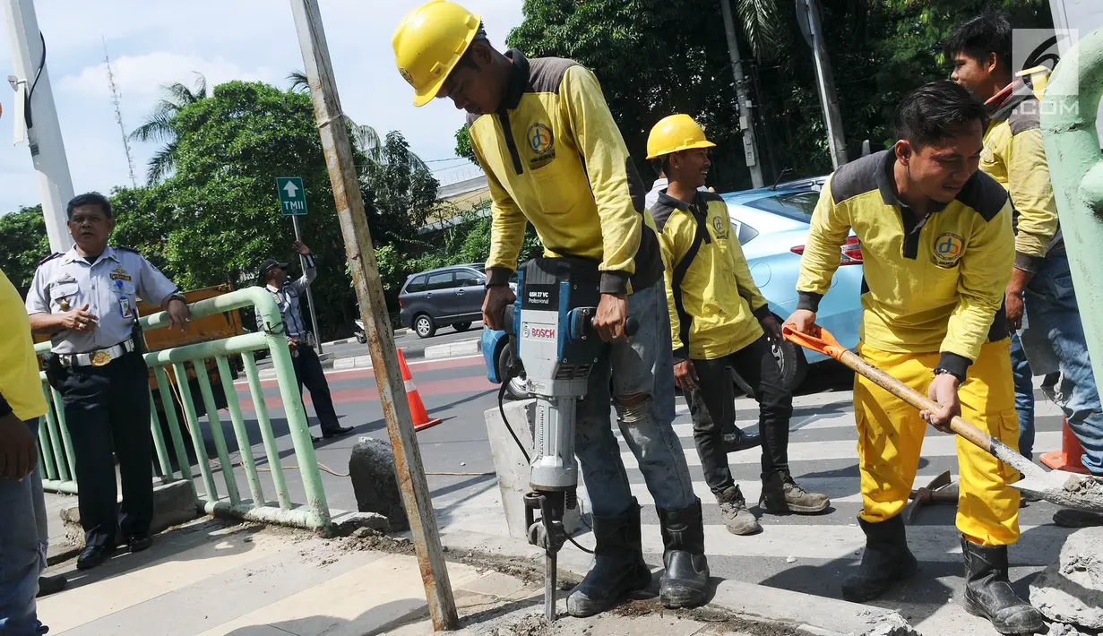 Aktivitas pekerja yang sedang membongkar pagar pembatas besi di kawasan Pinang Ranti, Jakarta, Senin (11/2). Zebra cross tersebut sempat menjadi perbincangan lantaran terhalang oleh pagar besi hijau setinggi 1 meter. (Liputan6.com/Herman Zakharia)