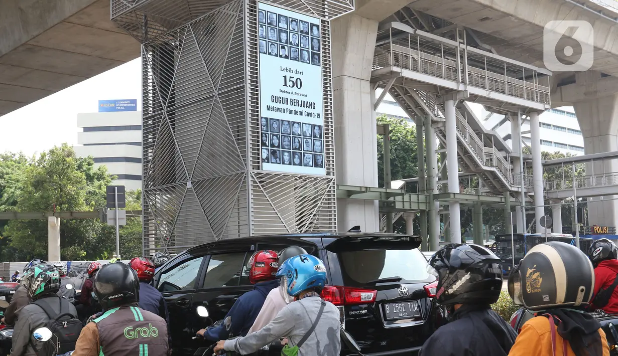 Pengendara melintasi videotron penghormatan kepada tenaga medis yang gugur akibat Covid-19 di tiang penyangga lintasan MRT, Jalan Sisingamangaraja, Jakarta, Jumat (18/9/2020). Keberadaan videotron tersebut diharap mampu membuat masyarakat waspada akan ancaman Covid-19. (Liputan6.com/Herman Zakharia)