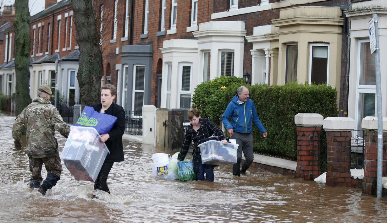 Warga menyelamatkan barang mereka saat banjir merendam wilayah Warwick Road Carlisle, Inggris, Minggu (6/12). Puluhan ribu rumah tidak punya listrik karena Badai Desmond yang menyebabkan banjir di Inggris utara dan sebagian Skotlandia (REUTERS/Phil Noble)