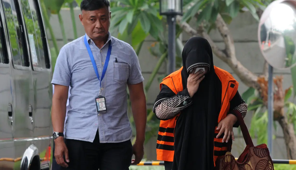 Anggota DPRD Kota Malang Een Ambarsari (kanan) menutupi wajah saat tiba di Gedung KPK, Jakarta, Selasa (2/10). Een menjalani pemeriksaan terkait dugaan menerima suap pembahasan APBD-P Pemkot Malang Tahun Anggaran 2015. (Merdeka.com/Dwi Narwoko)