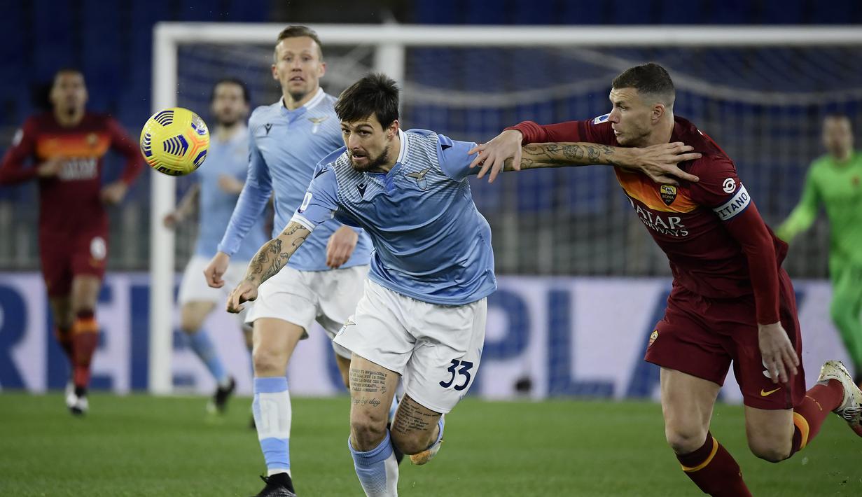 Bek Lazio, Francesco Acerbi (kiri) berebut bola dengan striker AS Roma, Edin Dzeko dalam laga lanjutan Liga Italia Serie A 2020/21 pekan ke-18 di Olympic Stadium, Roma, Jumat (15/1/2021). Lazio menang 3-0 atas AS Roma. (AFP/Filippo Monteforte)