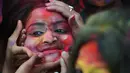 Wajah seorang perempuan yang dilumurkan bubuk warna selama mengikuti perayaan Holi di Kolkata, India (7/3). Selama perayaan tersebut, peserta saling melemparkan bubuk berwarna-warni atau saling menyiramkan air berwarna-warni. (AFP/Dibyangshu)