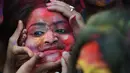 Wajah seorang perempuan yang dilumurkan bubuk warna selama mengikuti perayaan Holi di Kolkata, India (7/3). Selama perayaan tersebut, peserta saling melemparkan bubuk berwarna-warni atau saling menyiramkan air berwarna-warni. (AFP/Dibyangshu)