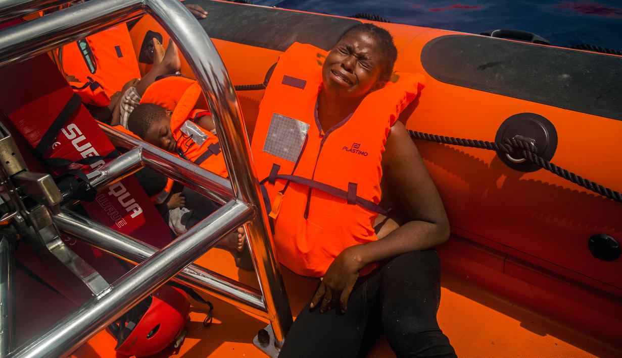 Seorang imigran Afrika sub-Sahara menangis usai diselamatkan dari atas perahu karet di tengah Laut Mediterania, lepas pantai Libya, Selasa (25/7). Di perahu karet itu, petugas penyelamat dari LSM Spanyol mememukan 13 mayat. (AP/Santi Palacios)