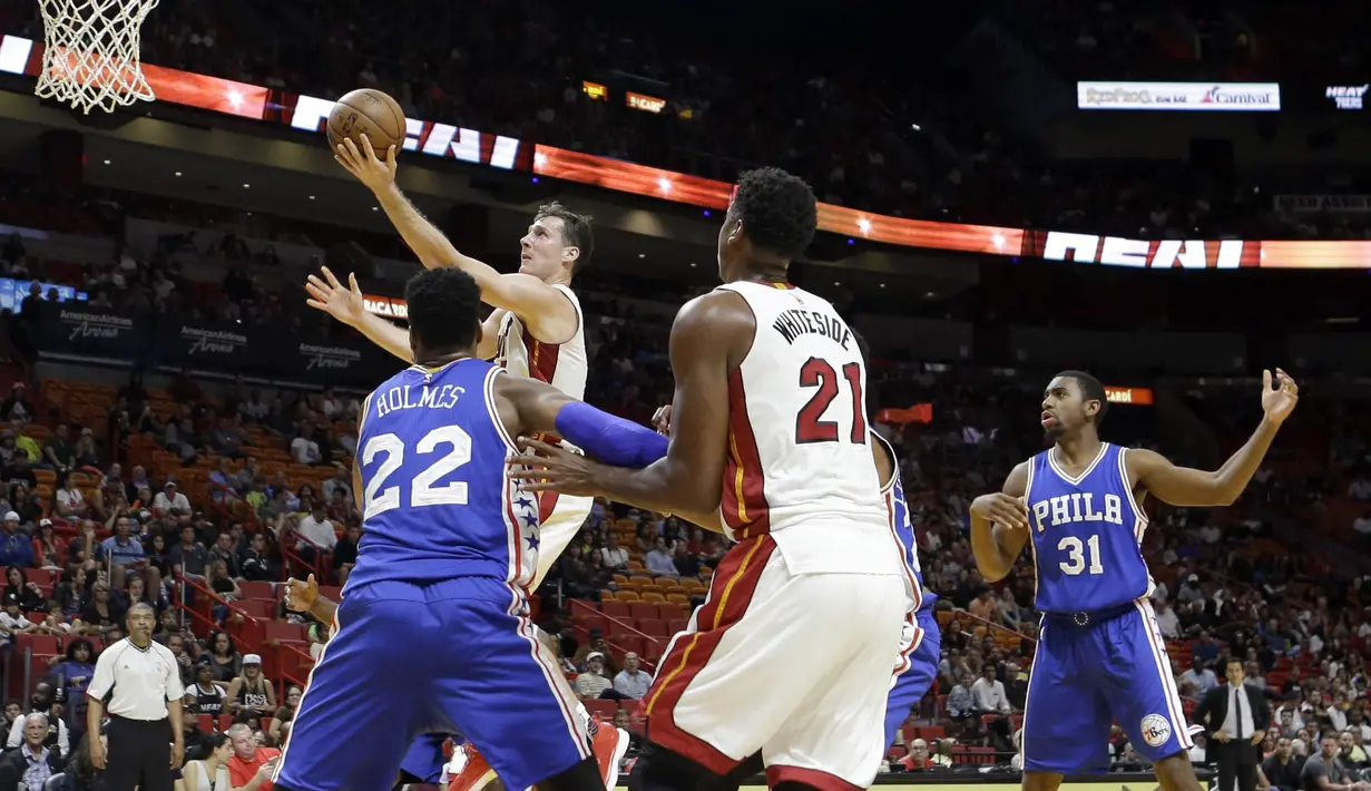 Aksi pemain Miami Heat, Goran Dragic #7 saat memasukan bola kedalam keranjang melewati hadangan pemain Philadelphia 76ers pada laga NBA preseason basketball game di Miami, Sabtu (22/10/2016) WIB. (AP/Alan Diaz)