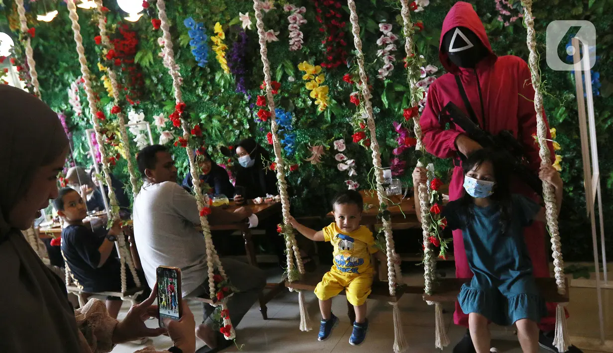 Pramusaji menggunakan kostum serial Netflix Squid Game di Cafe Strawberry, Jakarta, Sabtu (16/10/2021). Cafe tersebut melakukan inovasi dengan mengusung tema permainan yang ada dalam film asal Korea Selatan yakni Squid Game untuk memberikan daya tarik bagi pengunjung. (Liputan6.com/Herman Zakharia)