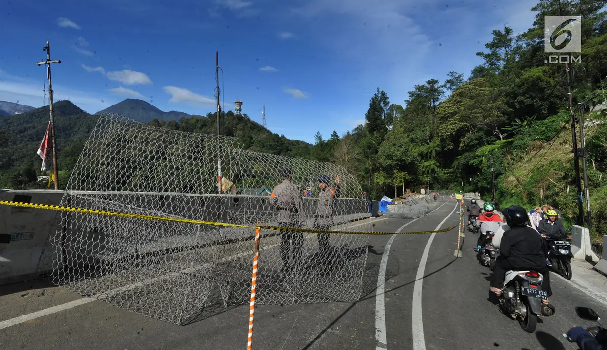 Petugas kepolisian menutup Jalur Puncak Bogor seusai longsor di kawasan  Ciloto, Kabupaten Cianjur, Jawa Barat, Kamis (29/3). Lokasi longsor tepat berada di puncak pass, yakni titik perbatasan antara Kabupaten Bogor dan Cianjur. (Merdeka.com/Arie Basuki)