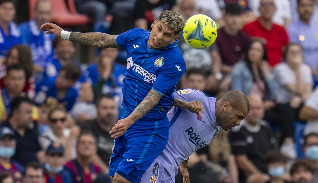 Pemain Barcelona Dani Alves (kanan) berduel memperebutkan bola dengan pemain Getafe Mathias Olivera pada pertandingan sepak bola La Liga di Stadion Coliseum Alfonso Perez, Getafe, Spanyol, 15 Mei 2022. Pertandingan berakhir imbang 0-0. (AP Photo/Manu Fernandez)