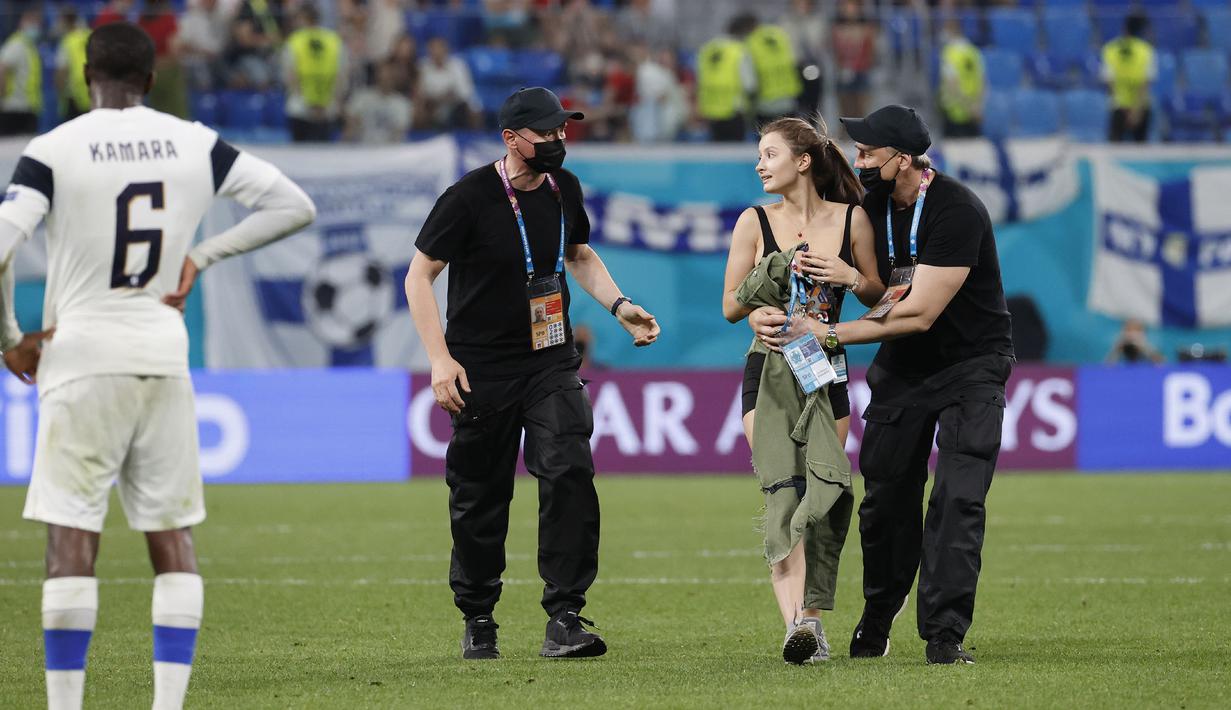 Menariknya, pakaian hitam wanita itu mempromosikan sesuatu yaitu WTF Coin. Menurut informasi yang dilansir oleh The Sun, WTF Coin adalah saingan Bitcoin, uang digital yang saat ini sedang naik daun. (Foto: AP/Pool/Anatoly Maltsev)