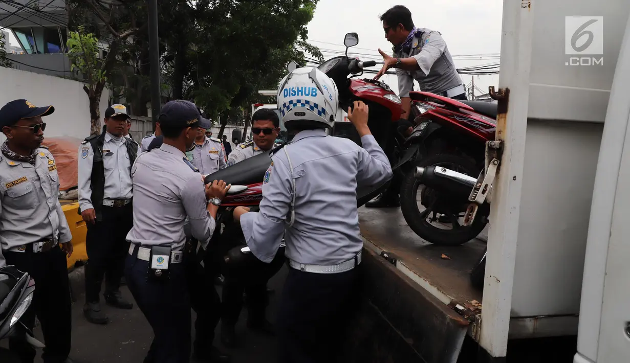 Petugas Dishub DKI mengangkut sepeda motor yang parkir sembarangan saat operasi penertiban di kawasan Pasar Tanah Abang, Jakarta, Senin (21/5). Razia pada hari kelima puasa itu untuk menertibkan parkir liar selama Ramadan. (Liputan6.com/Arya Manggala)