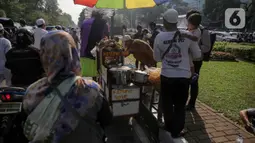 Pedagang ketupat sayur melayani pembeli saat berjualan di tengah aksi reuni 212, sekitaran Jalan Medan Merdeka Barat, Jakarta, Senin (2/12/2019). Sejumlah PKL meraup untung dengan berjualan di tengah ribuan massa Persaudaraan Alumni 212 yang mengikuti reuni di Monas. (Liputan6.com/Faizal Fanani)