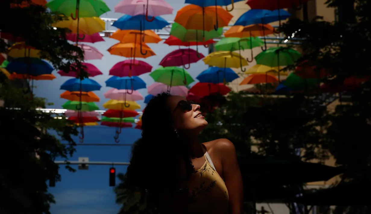 Julia Pena (19) dari Miami menikmati instalasi seni yang bernama Umbrella Sky di Coral Gables, Florida, 16 Juli 2018. Coral Gables merupakan kota ketiga di AS yang menjadi tuan rumah bagi instalasi seni yang berlangsung hingga Agustus. (AP/Brynn Anderson)