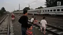 Anak-anak didampingi orang tuanya melihat kereta yang melintas saat menunggu waktu berbuka puasa atau ngabuburit di rel kereta Double Double Track (DDT) di Jakarta, Senin (21/5). (Merdeka.com/Iqbal S Nugroho)
