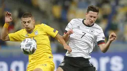Gelandang Jerman, Julian Draxler berebut bola dengan bek Ukraina, Vitaliy Mykolenko pada pertandingan  UEFA Nations League di Stadion Olimpiyskiy di Kyiv, Ukraina, Sabtu (10/10/2020). Jerman menang 2-1 atas Ukraina. (AP Photo/Efrem Lukatsky)