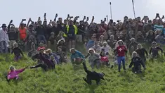 Para peserta bersaing dalam perlombaan menuruni bukit putri selama kontes Cheese Rolling di Cooper's Hill di Brockworth, Gloucestershire, Senin 29 Mei 2023. (AP Photo/Kin Cheung)