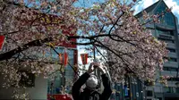 Seorang pria mengenakan masker mengambil gambar pohon sakura di taman Ueno di Tokyo, Jepang (12/3/2020).  Di tengah kekhawatiran akan penyebaran virus corona COVID-19, ahli meteorologi memprediksi bunga sakura mulai mekar sekitar 17 Maret di Tokyo.  (AFP/Philip Fong)