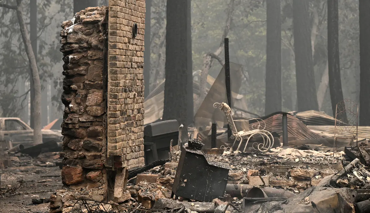 Rumah dan barang-barang pribadi yang terbakar di Dixie Fire masih membara di daerah Indian Falls Plumas County, California (26/7/2021). (AFP/Robyn Beck)