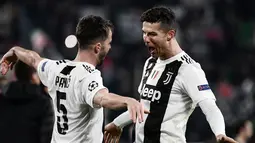 Pemain Juventus Miralem Pjanic (kiri) merangkul Cristiano Ronaldo usai mereka mengalahkan Atletico Madrid pada leg kedua babak 16 besar Liga Champions di Allianz Stadium, Turin, Selasa (12/3). Atletico tersingkir dari Liga Champions.(Marco BERTORELLO/AFP)