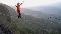 Atlet olahraga ekstrem Andi Ardi berjalan di atas tali di ketinggian 740 meter (2.427 kaki) di Gunung Nglanggeran di Yogyakarta (9/9/2019). Ardi melakukan aksi tersebut sebagai bagian dari kampanye pariwisata untuk mempromosikan tempat yang indah. (AFP Photo/Agung Supriyanto)