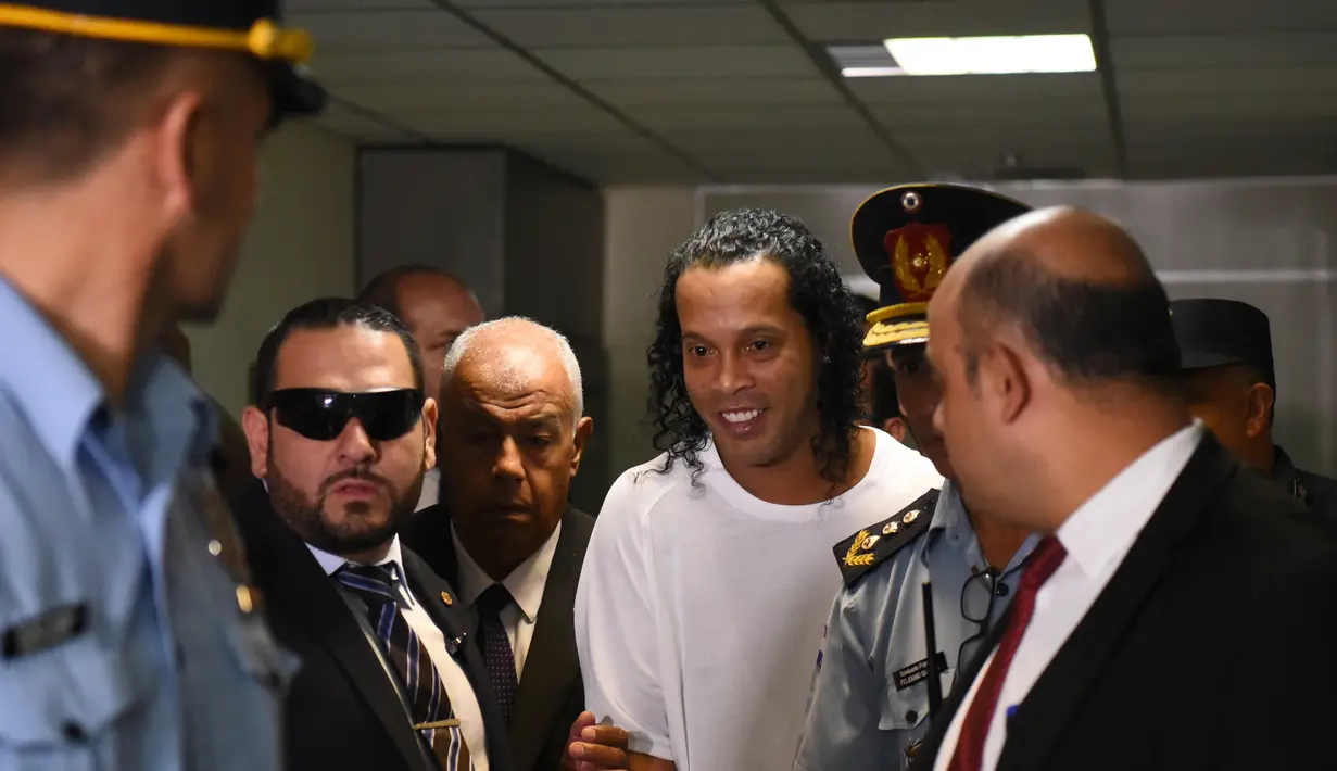 Mantan pemain Barcelona asal Brasil, Ronaldinho (tengah) tiba di Asuncion's Justice Palace untuk bersaksi tentang masuknya dia yang tidak teratur ke negara itu, di Asuncion, pada 6 Maret 2020. Ronaldinho mengumumkan dirinya positif Covid-19 pada Minggu (25/10/2020) malam WIB. (AFP/Norberto Duarte)