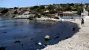 Turis berjalan di pinggir pantai yang tercemar tumpahan minyak di Pulau Salamina, Yunani, Selasa (12/9). Tumpahan bahan bakar itu kemudian meluas hingga 1,5 km dan kini mengotori pasir dan bebatuan karang sepanjang pesisir pantai. (AP/Petros Giannakouris)