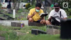 Peziarah membaca doa di salah satu makam di Tempat Pemakaman Umum Karet Bivak, Jakarta, Sabtu (18/4/2020). Selama masa PSBB, peziarah yang memasuki kawasan TPU dibatasi dan diwajibkan menggunakan masker sebagai langkah pencegahan penyebaran virus Covid-19. (Liputan6.com/Helmi Fithriansyah)