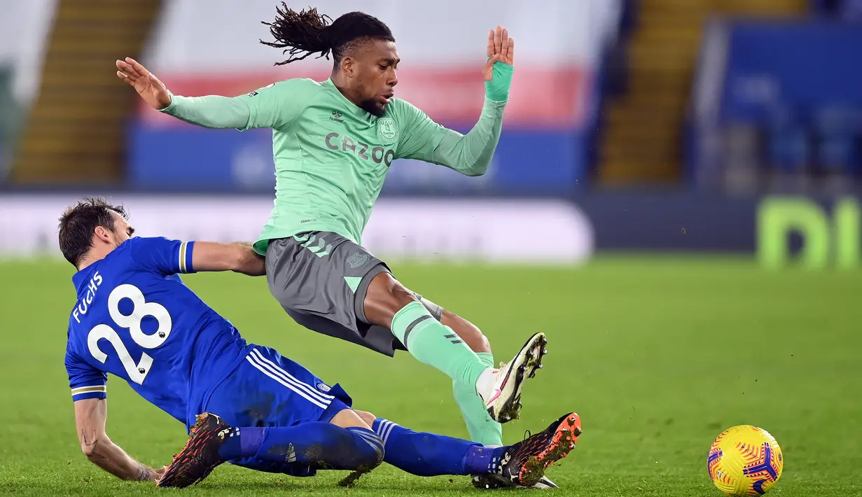Gelandang Everton, Alex Iwobi, berebut bola dengan bek Leicester City, Christian Fuchs, pada laga lanjutan Liga Inggris di King Power Stadium, Kamis (17/12/2020) dini hari WIB. Everton menang 2-0 atas Leicester City. (AFP/Michael Regan/pool)