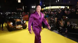 Dwayne Johnson berpose untuk fotografer saat tiba pada pemutaran perdana film 'Black Adam' di London, Inggris, 18 Oktober 2022. Dwayne Johnson mengenakan tuksedo satin ungu yang nyentrik. (Photo by Vianney Le Caer/Invision/AP)