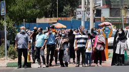 Warga Iran, yang mengenakan masker menunggu di penyeberangan pejalan kaki, di ibu kota Teheran, Sabtu (3/7/2021). Presiden Hassan Rouhani mengaku khawatir Iran akan dilanda gelombang kelima pandemi Covid-19 karena kemunculan virus corona varian Delta. (ATTA KENARE/AFP)