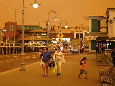 Sejumlah orang berjalan saat kabut asap menyelimuti langit di Fisherman's Wharf, San Francisco, Amerika Serikat, Rabu (9/9/2020). Kebakaran hutan di seluruh Barat mengakibatkan langit San Francisco hingga Seattle berwarna oranye yang menakutkan. (AP Photo/Eric Risberg)
