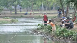 Warga memancing di danau Taman Cempaka, Cipayung, Jakarta Timur, Minggu (7/7/2019). Selain dikelilingi pepohonan yang rindang, taman ini dilengkapi berbagai sarana seperti trek jogging, wahana bermain anak, hingga danau buatan yang ramai didatangi warga untuk memancing. (merdeka.com/Iqbal S Nugroho)