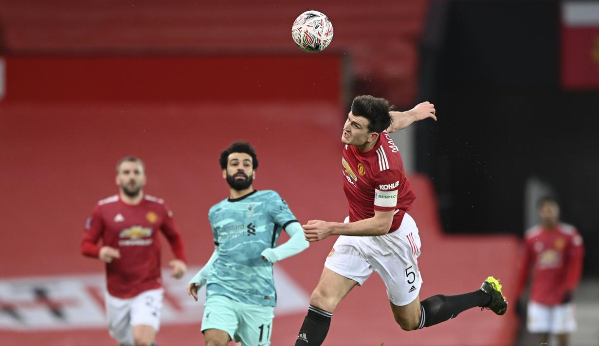 Pemain Manchester United, Harry Maguire (kanan) berusaha menghalau bola pada laga babak keempat FA Cup 2020-21 di Old Trafford, Senin (25/01/2021). (Foto: AP/Pool/Laurence Griffiths)