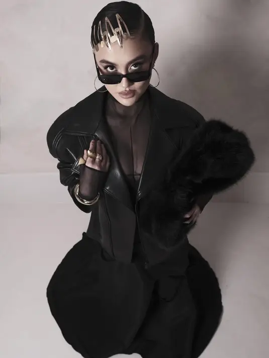 Detail bahu yang structured dan kerah lebar memberi kesan powerful, sementara material kulit hitam menguatkan aura bold yang jadi ciri khas gaya Agnez. Di balik jaketnya, Agnez mengenakan bralette hitam yang dipadukan dengan sheer turtleneck berlengan panjang. [@agnezmo].