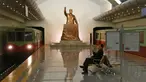 Seorang pria membaca sambil menunggu kereta dengan latar belakang patung mendiang Presiden Korea Utara Kim Il Sung di stasiun kereta bawah tanah Kaeson di Pyongyang, Korea Utara (23/11/2019). Stasiun Kaeson adalah stasiun di Jalur Chŏllima Metro Pyongyang. (AP Photo/Dita Alangkara)