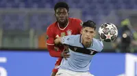 Gelandang Lazio, Joaquin Correa berebut bola dengan bek  Bayern Munchen, Alphonso Davies dalam pertandingan leg pertama babak 16 besar Liga Champions, di Stadion Olimpico, Roma, Rabu (24/2) dini hari WIB. Bayern Muenchen sukses meraih kemenangan 4-1 atas tuan rumah Lazio. (AP Photo/Gregorio Borgia)