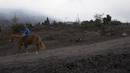 Seorang remaja mengendarai kuda di jalan tanah yang tertutup abu saat terjadi letusan gunung Pacaya di San Francisco De Sales, Guatemala, Selasa (23/3/2021). Abu juga menghujani sejumlah pesawat di kota itu hingga pihak berwenang pun menutup bandara internasional La Aurora (AP Photo/Moises Castillo)