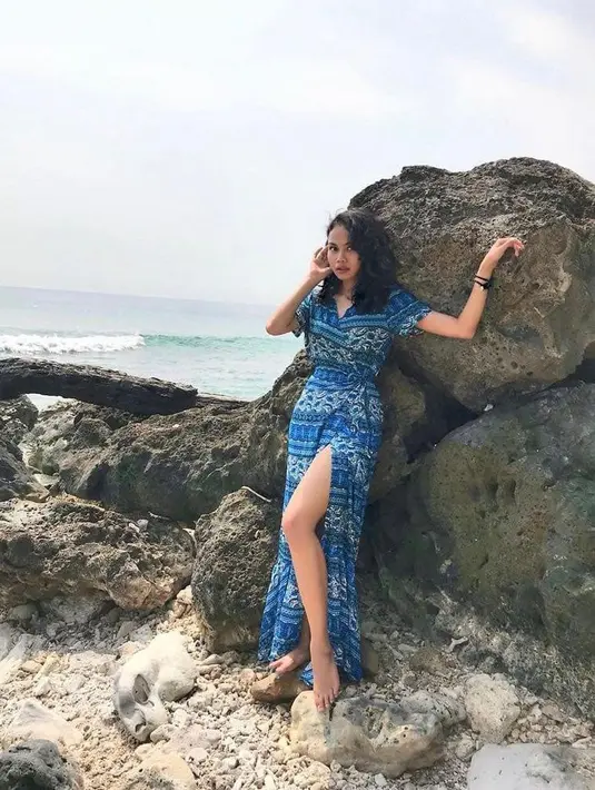 Berpose di bebatuan pantai, Dea Panendra terlihat cantik mengenakan slip dress tenun. (Instagram/deapanendra).