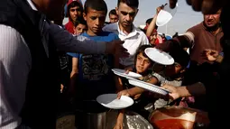 Sejumlah anak saat mengambil makanan saat mengungsi di kamp Khazer, Irak, (11/11). Warga terpaksa melarikan diri saat Pasukan Irak dan kelompok militan ISIS bentrok memberebutkan kota Mosul. (REUTERS/Zohra Bensemra)
