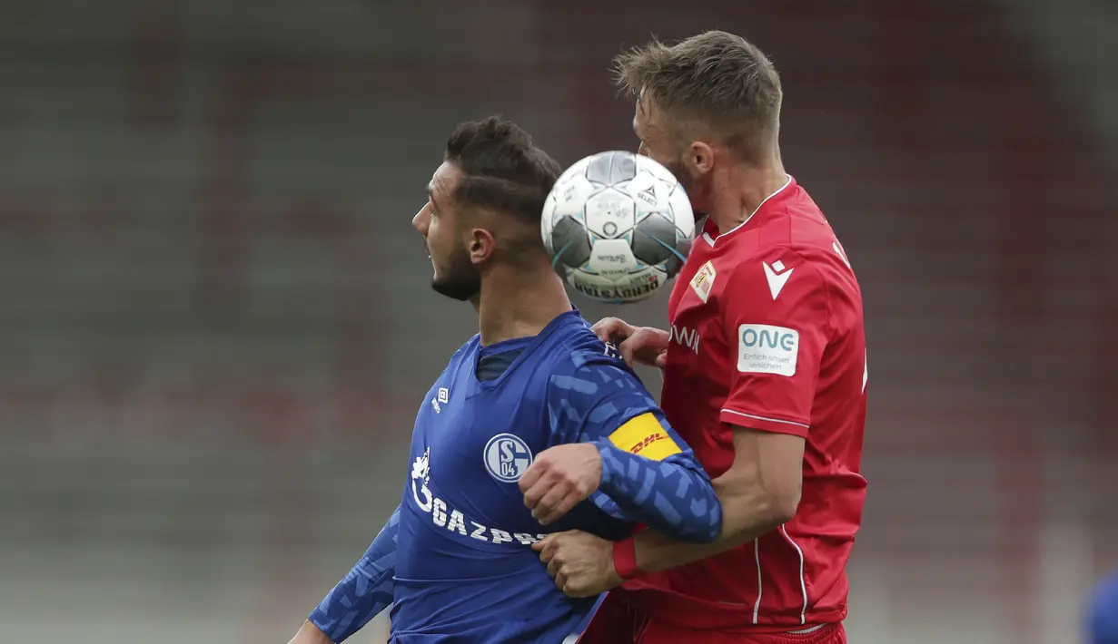 Pemain Union Berlin, Florian Huebner, berebut bola dengan pemain Schalke, Ahmed Kutucu, pada laga Bundesliga di Weserstadion Minggu (7/6/2020). Kedua tim bermain imbang 1-1. (AP/Michael Sohn)