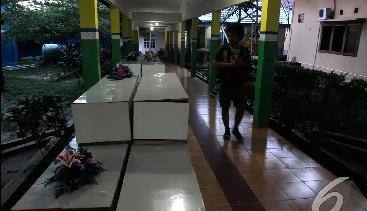 Seorang wartawan melintasi deretan peti jenazah untuk penumpang AirAsia QZ8501 di RSUD Sultan Imanuddin, Pangkalan Bun, Kalimantan Tengah, Kamis (1 /1/2015). (Liputan6.com/Herman Zakharia)